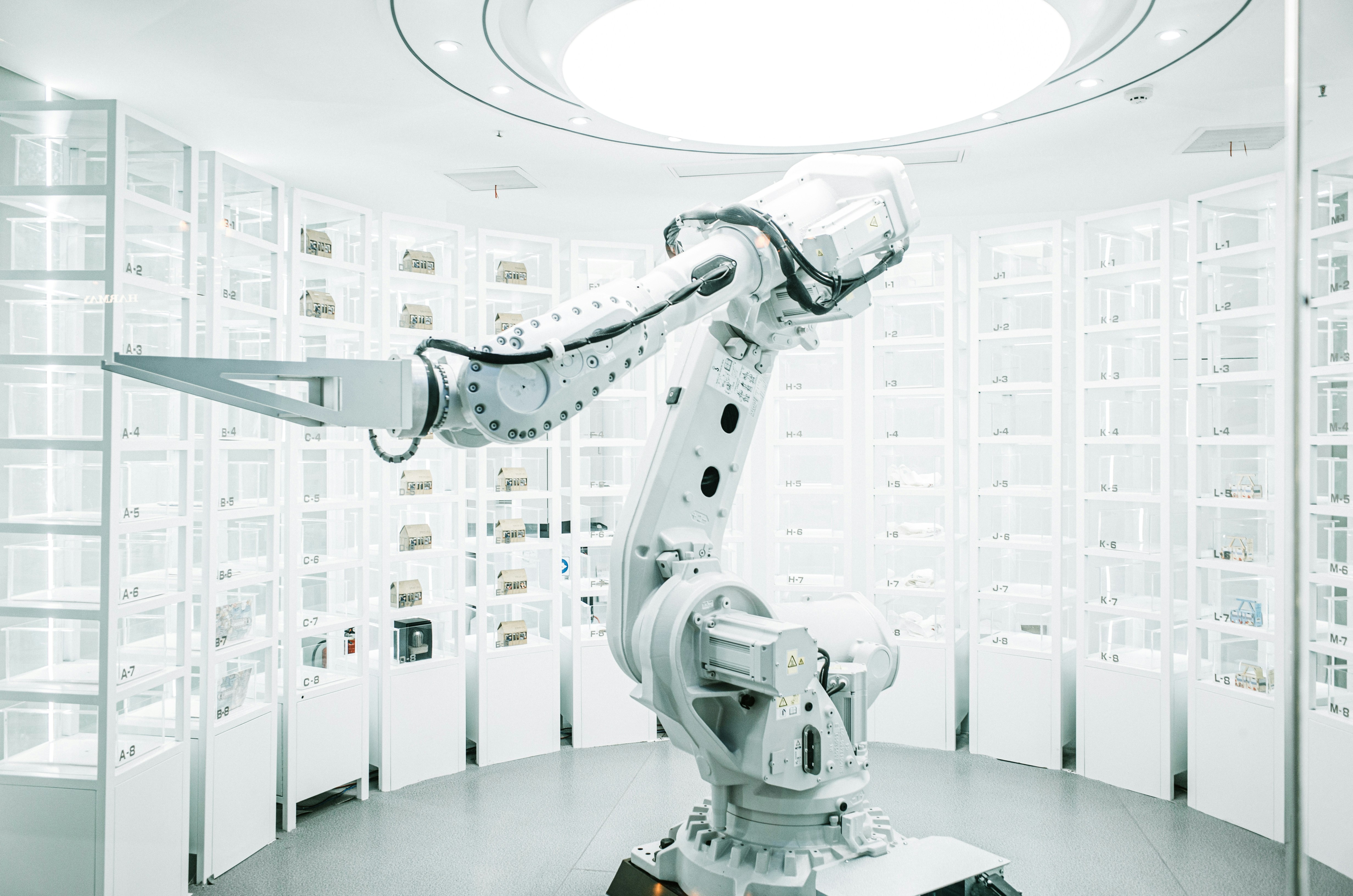 A robotic arm in a modern, automated laboratory filled with storage units.